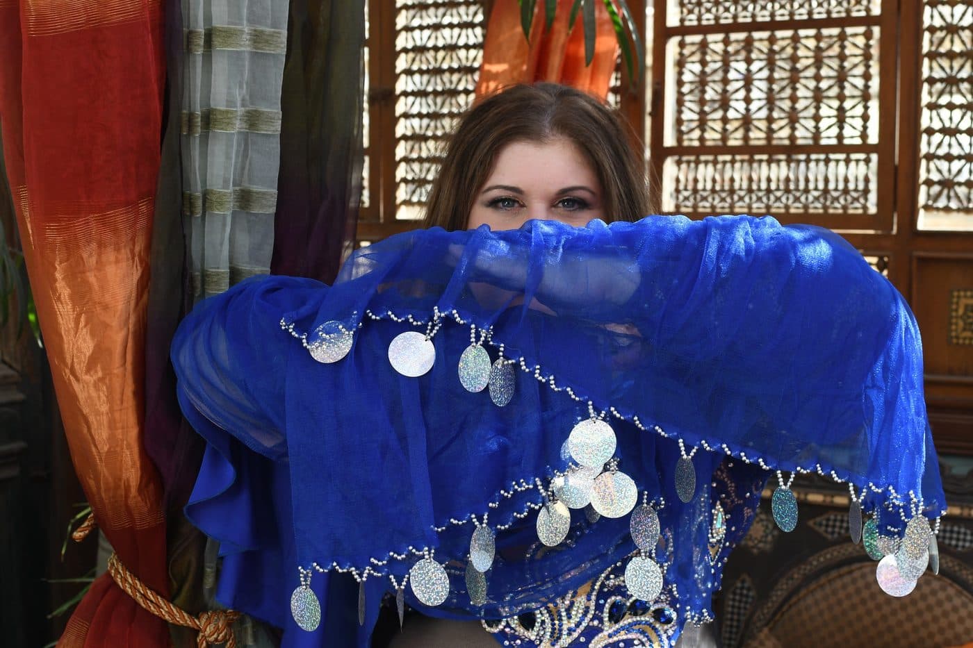 A dancer framed by a blue coin-trimmed veil