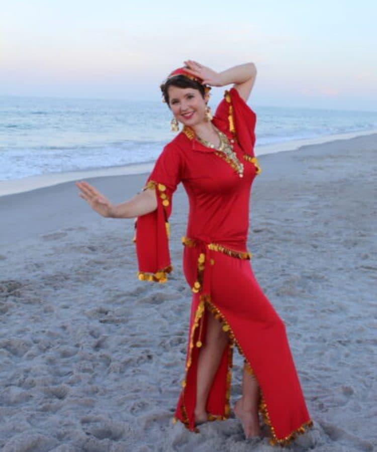 Rachel dancing on the beach in a red belly dance dress